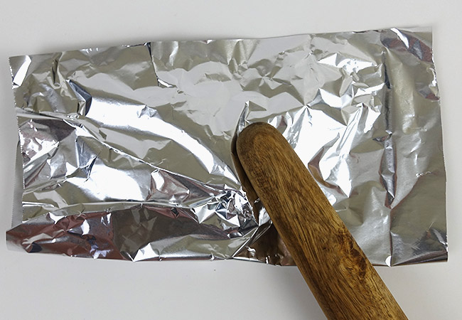 Fish inside aluminum foil being euthanized with a blunt object