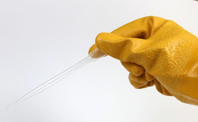 Holding plastic pipette aquarium syringe with hand covered by aquarium glove